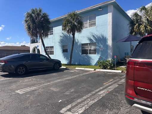 A car is parked in a parking lot in front of a blue building.