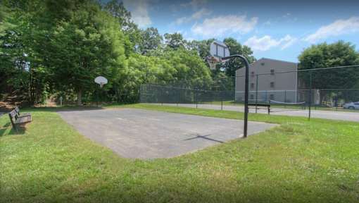 A basketball court surrounded by a fence and trees.
