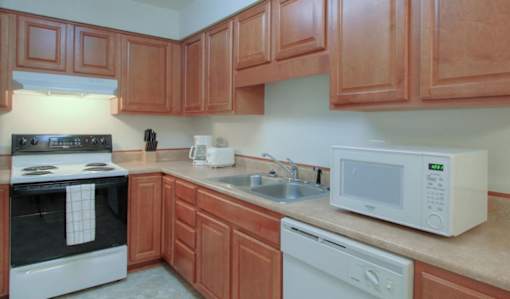 A kitchen with brown cabinets and white appliances.