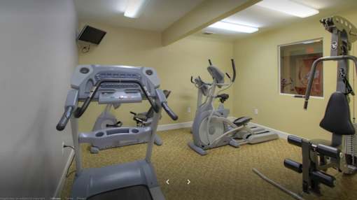 A gym room with a treadmill, exercise bike, and other equipment.