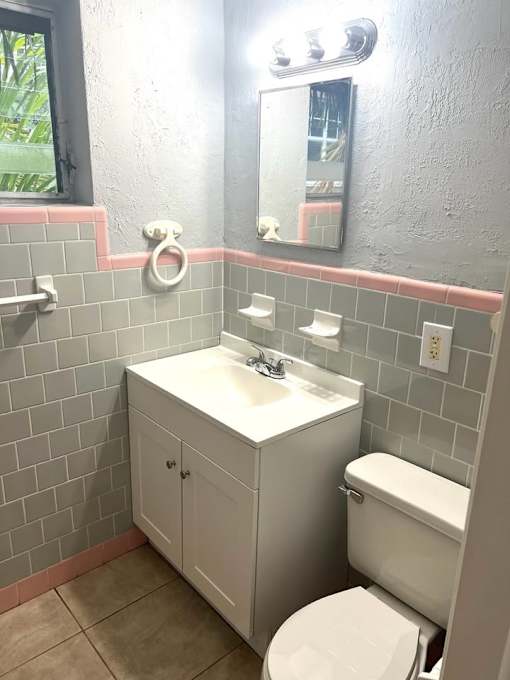 A bathroom with a toilet, sink, and mirror.