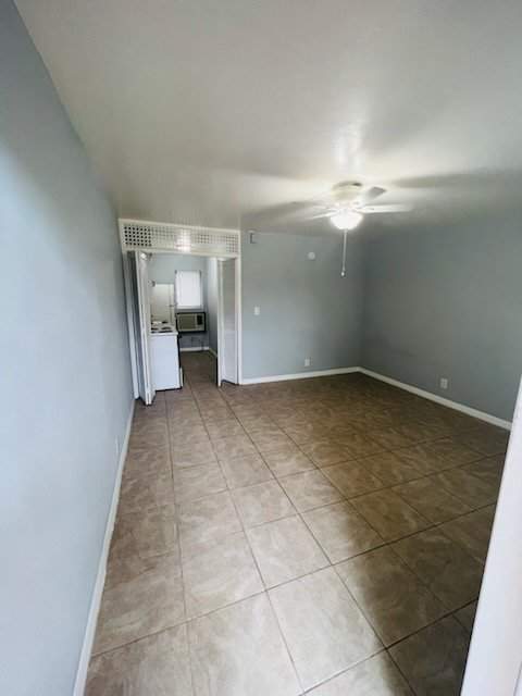A room with a ceiling fan and tile flooring.