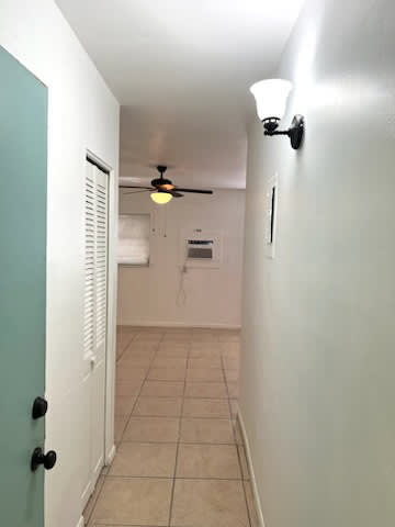 A white door with black handles is on the left of a hallway with a light blue door.