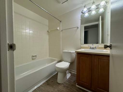 A white tiled bathroom with a toilet, sink, and bathtub.