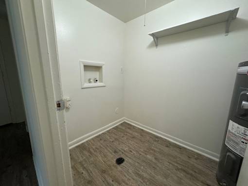 A small room with a white wall and a wooden floor.