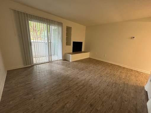 A room with wooden flooring and a window with curtains.