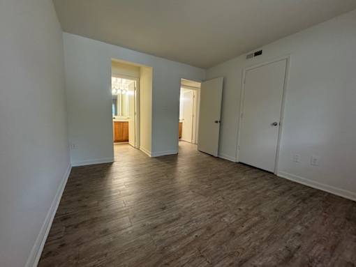 A room with wooden flooring and white walls.