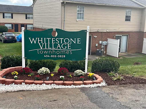 A sign for Whitestone Village townhomes with a phone number on it.