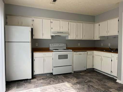 A kitchen with white appliances and cabinets.