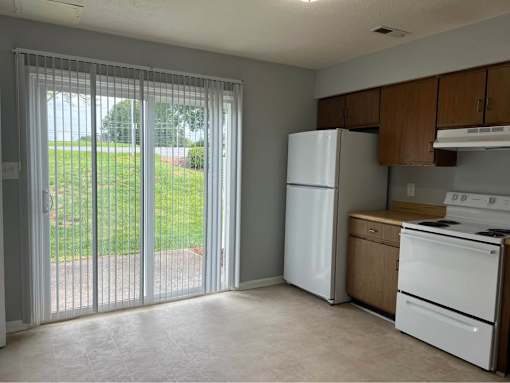 A kitchen with white appliances and a sliding glass door.