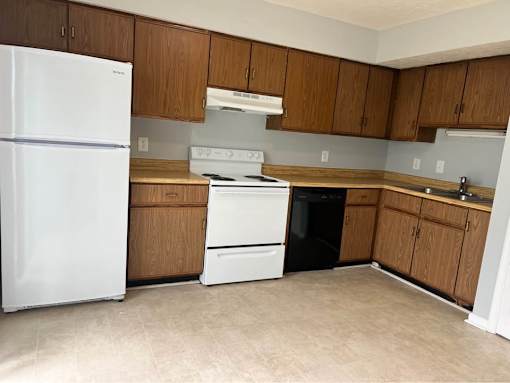 A kitchen with a white refrigerator, wooden cabinets, and a white stove top oven.