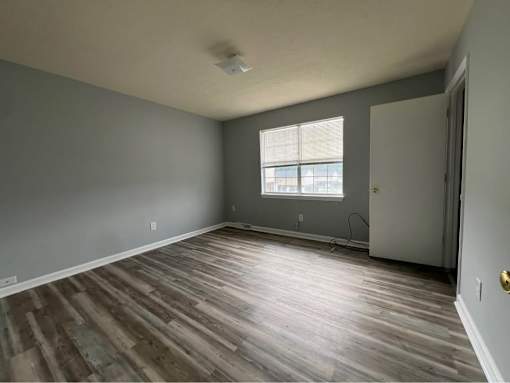 A room with wooden flooring and a window.