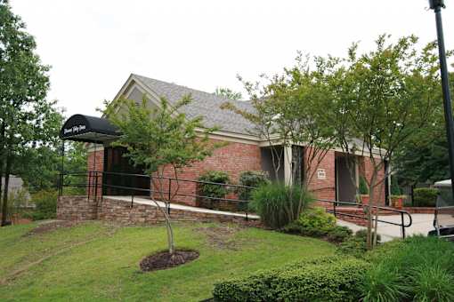 A building with a black awning is surrounded by greenery.