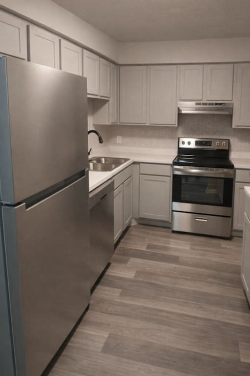 A modern kitchen with a stainless steel refrigerator and oven.
