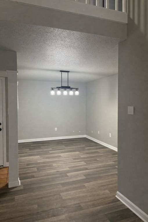 A room with a light hanging from the ceiling and a wooden floor.