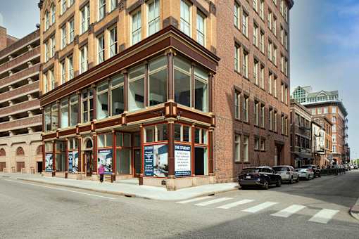 A street view of a building with a large glass window and a sign that says "RENT".