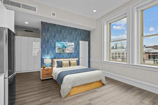 A bedroom with a bed, nightstand, and a painting on the wall.
