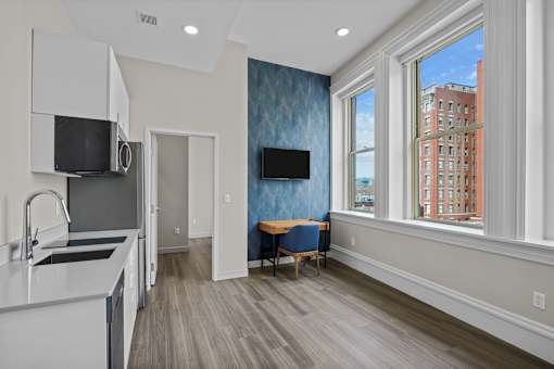 A kitchen with a blue wallpapered wall and a window overlooking a city.