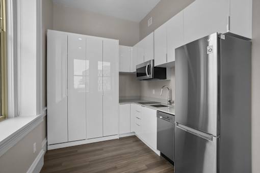 A modern kitchen with a stainless steel refrigerator and white cabinets.