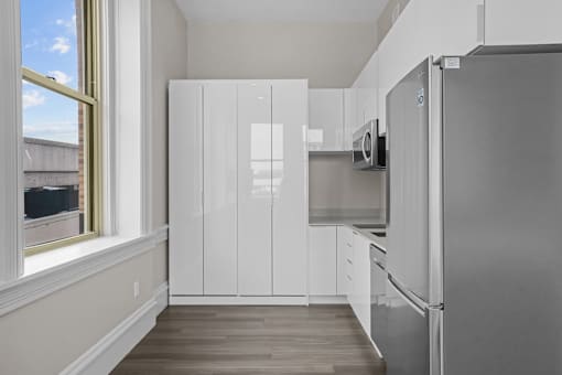 A kitchen with white cabinets and a stainless steel refrigerator.