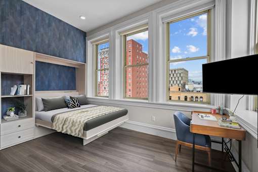 A bedroom with a bed, desk, and chair.