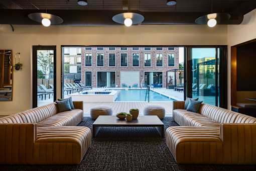 A modern living room with a large window overlooking a pool and buildings outside.