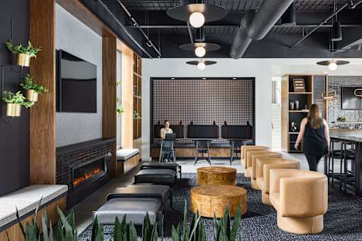 A woman is walking through a modern room with a fireplace and a long table.