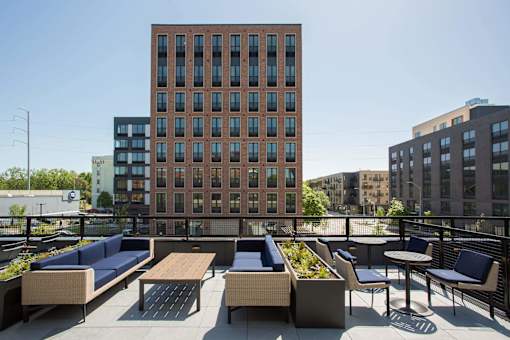 A brown building with a balcony that has a table and chairs.