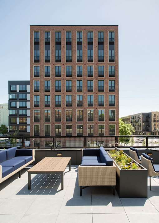 A large red brick building with a balcony containing a table and chairs.