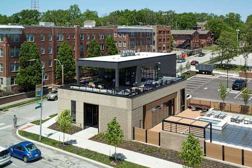A modern building with a glass entrance sits in front of a parking lot.