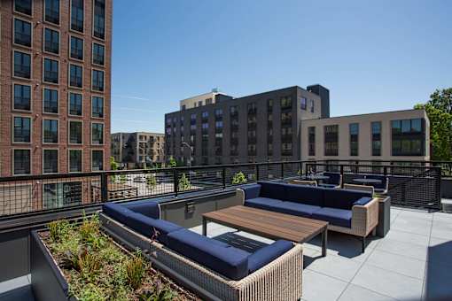 A rooftop patio with a couch and a table.