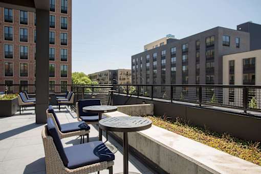 A patio with chairs and tables is surrounded by buildings.