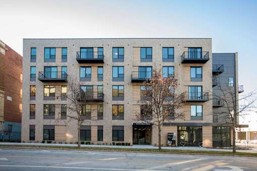 A modern apartment building with balconies and a storefront on the ground floor.