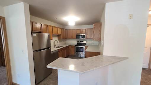 A kitchen with a refrigerator, microwave, oven, and stove.
