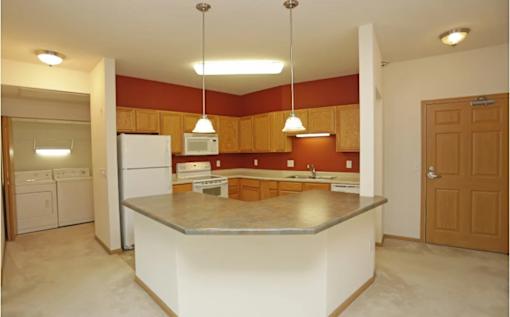 A kitchen with a white island and brown cabinets.