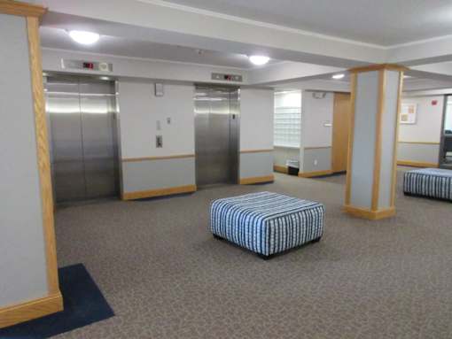 A room with a striped ottoman and two elevators.