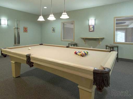A pool table in a room with a light blue wall and a mirror.