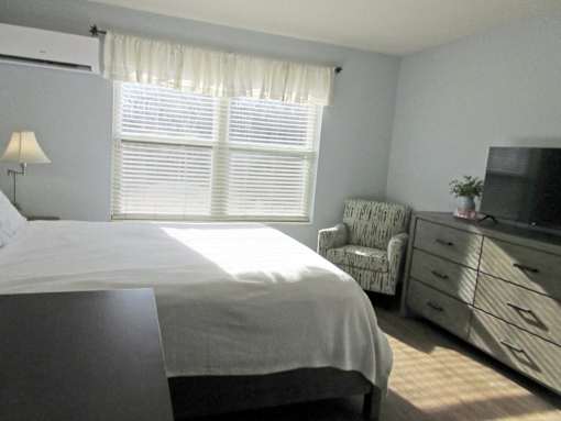A bedroom with a bed, chair, and television.
