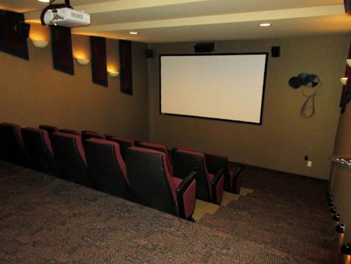 A movie theater with a large screen and red seats.