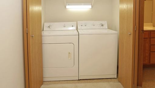 A pair of white front loading washing machines in a small laundry room.