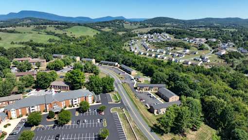 A bird's eye view of a residential area with houses, a parking lot, and a road.