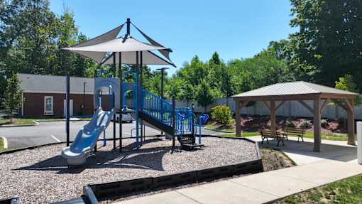 A playground with a blue slide and a canopy.