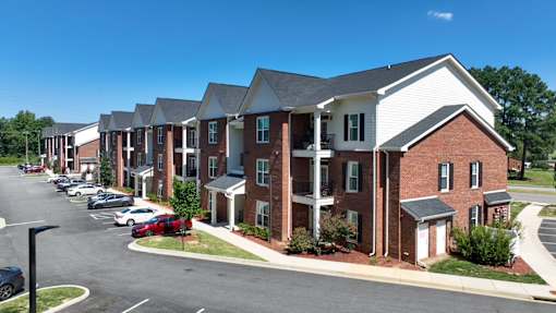 A row of townhouses with a parking lot in front.
