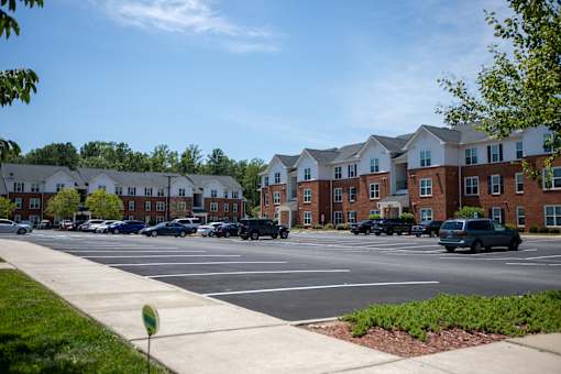 A parking lot in front of a row of apartment buildings.