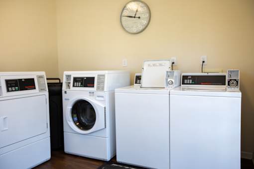 A row of white front load washing machines in a laundry room.