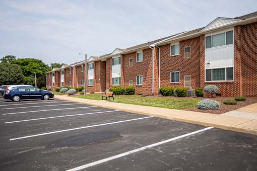 A parking lot in front of a brick apartment building.