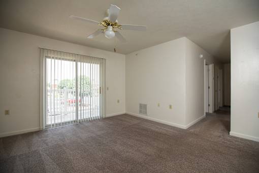 A room with a ceiling fan and carpeted floor.