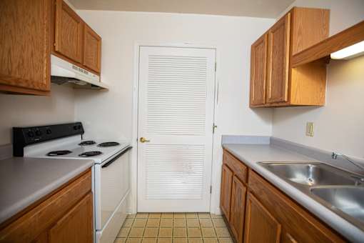 A kitchen with wooden cabinets and a white door.