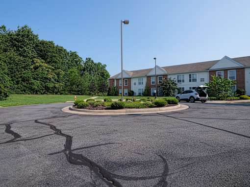A parking lot with a white car and a building in the background.