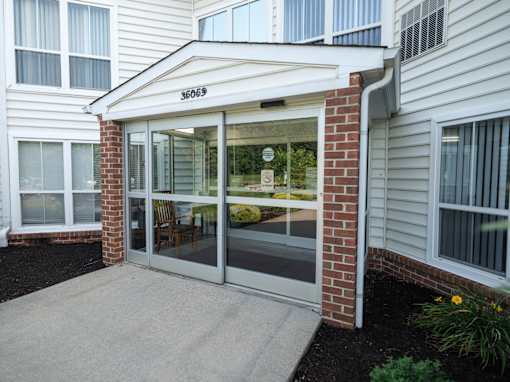 The entrance to a building with a glass door and a brick pillar.